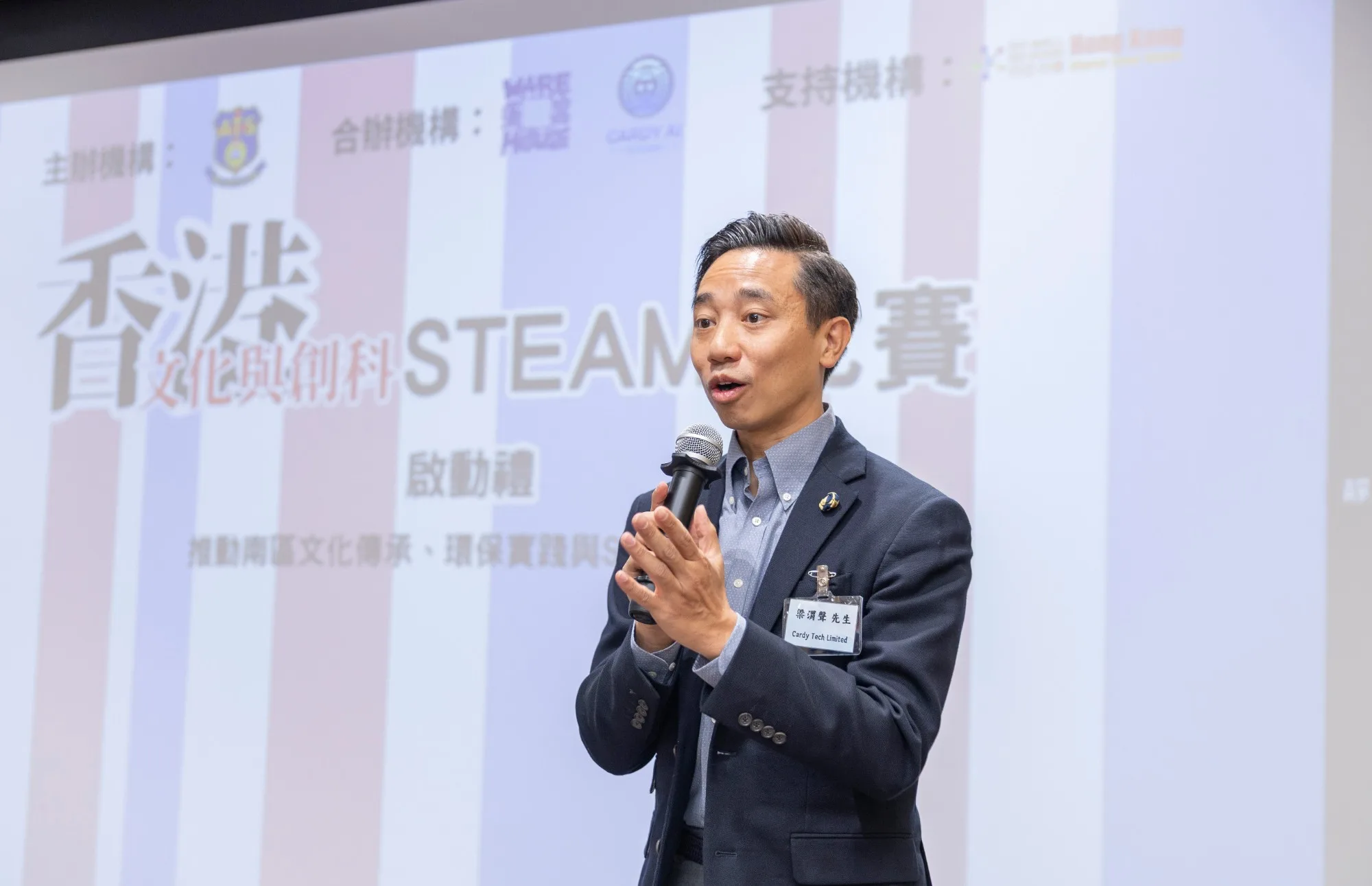A Cardy Tech representative gives a speech with a microphone at the launch ceremony of the "Hong Kong Culture and Technology STEAM Competition"
