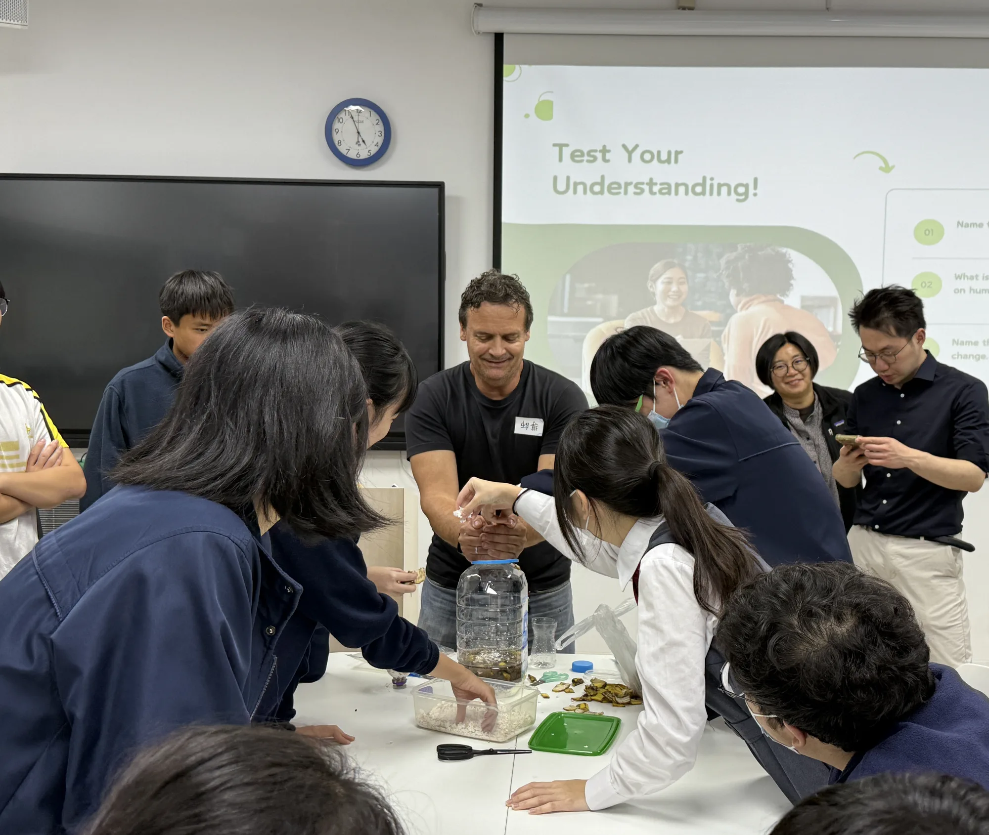 環保工作坊現場，導師帶領學生利用果皮等廚餘材料放入透明塑膠罐，動手製作環保酵素。